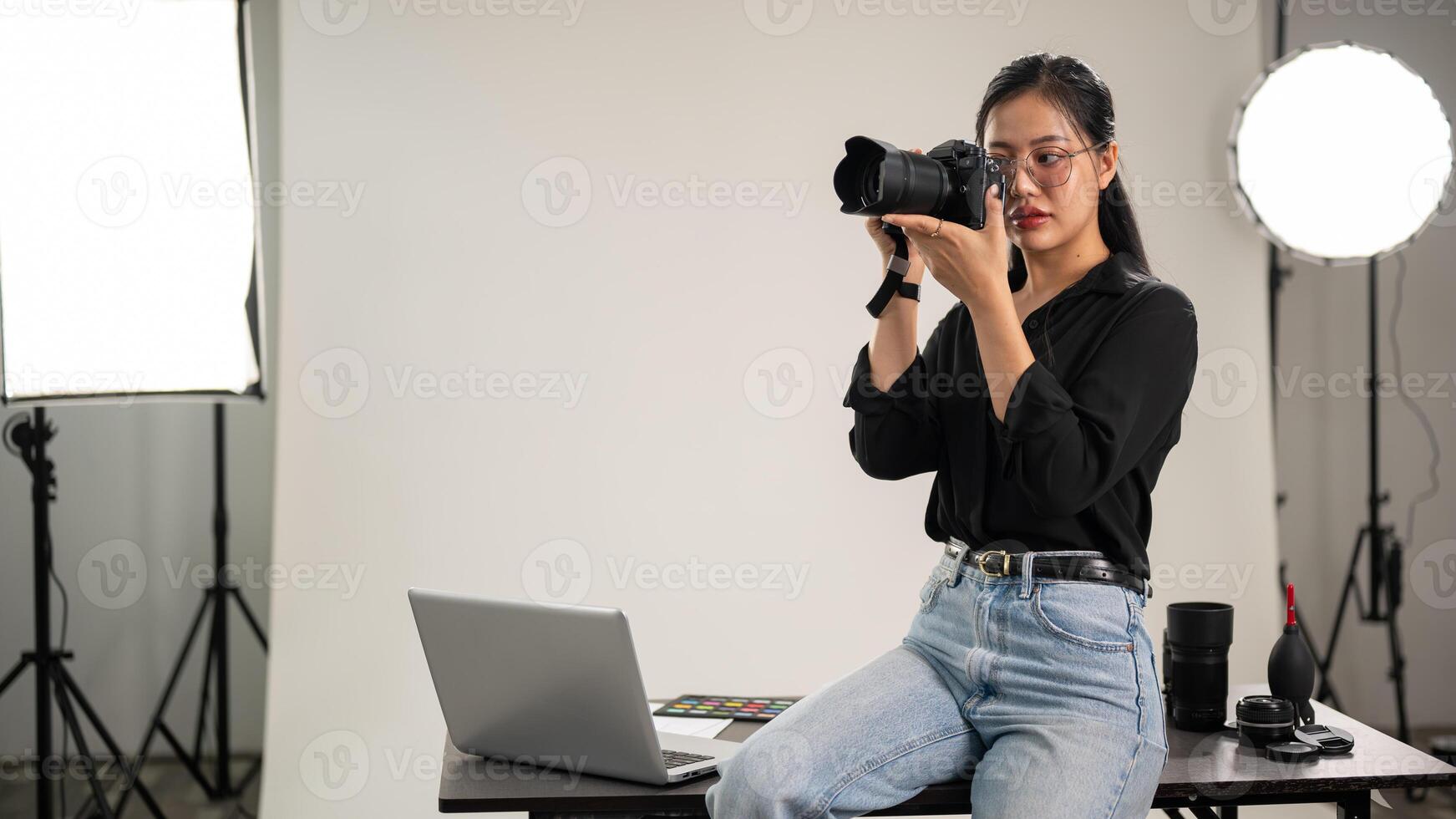 un hembra fotógrafo es tomando fotos, participación un cámara cerca su rostro, trabajando en un estudio. foto