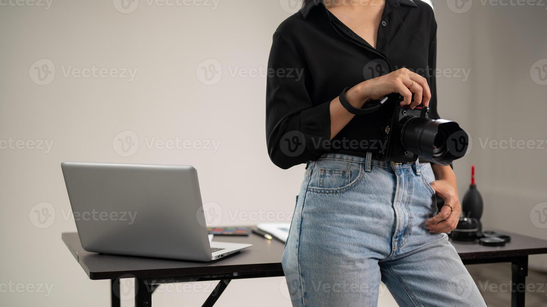 A cropped shot of a female photographer is standing in her studio with a DSLR camera in her hand. photo