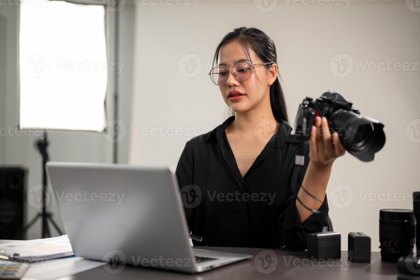 un profesional asiático hembra fotógrafo es enfoque en comprobación imágenes en su ordenador portátil. foto