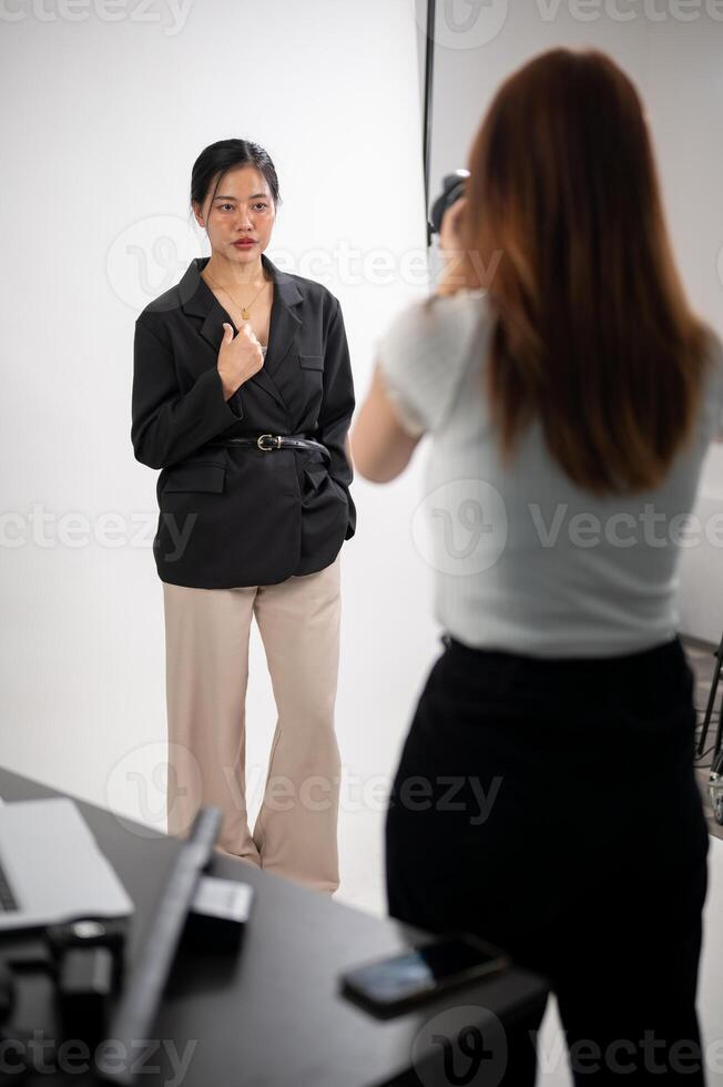 An attractive young Asian female model is posing for a photographer, taking a photoshoot in a studio photo