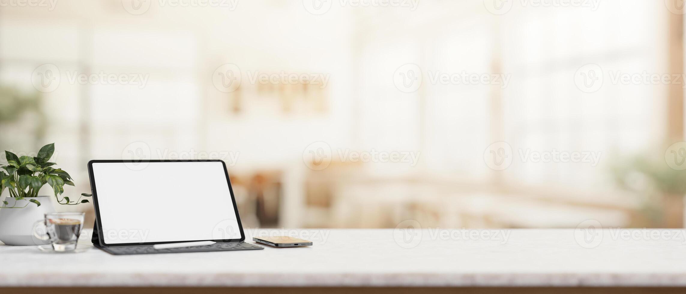 A table featuring a white-screen digital tablet with a blurred background of a coffee shop. photo