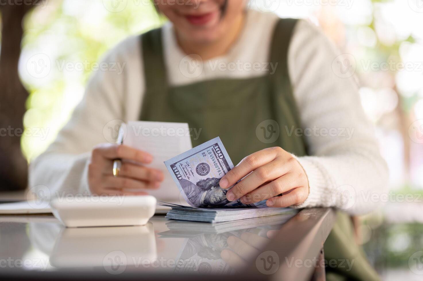 A cropped shot of a female small business owner managing her shop budget, calculating, counting cash photo