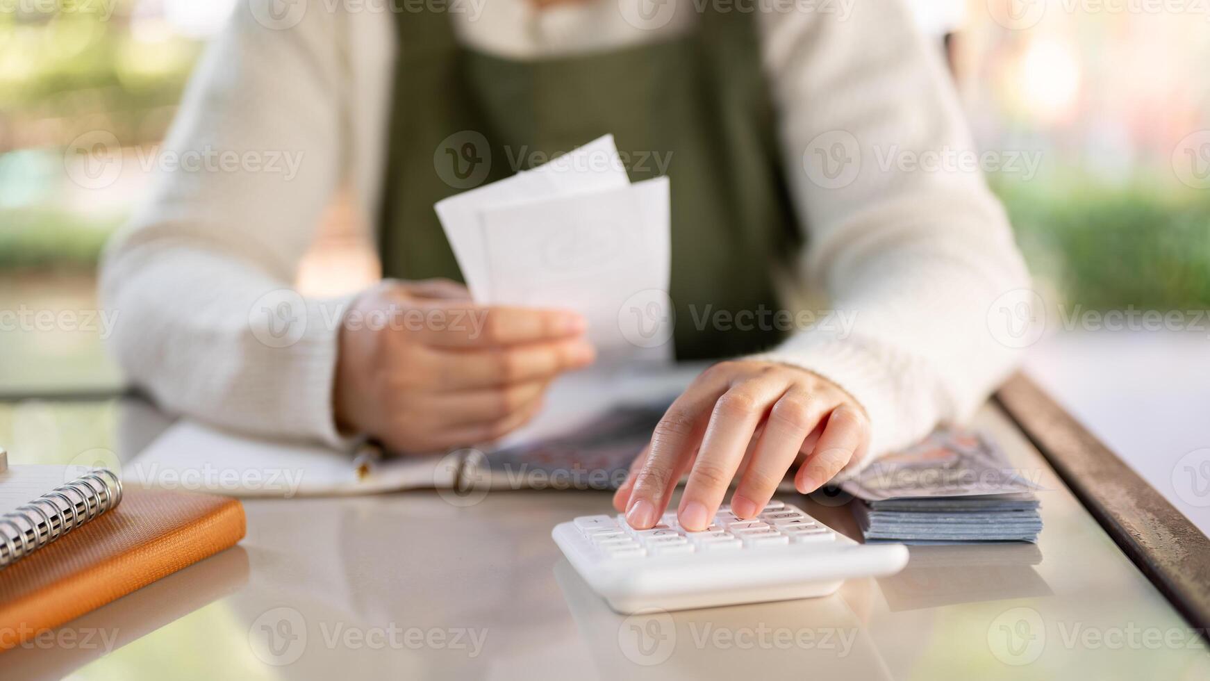 A female small business owner using a calculator, calculating bills, planning her shop expenses. photo