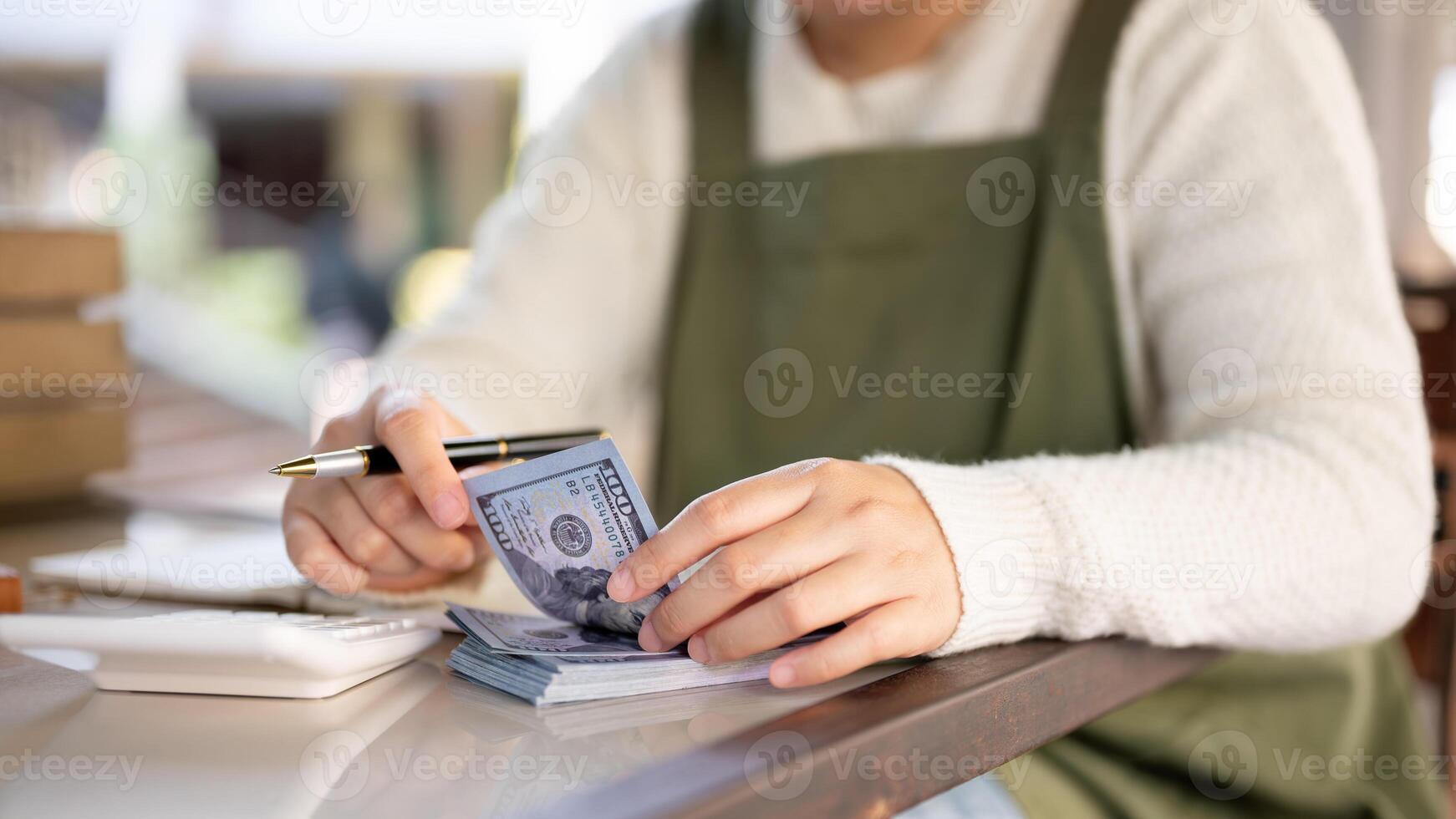 un recortado Disparo de un hembra pequeño negocio propietario gerente su tienda presupuesto, calculador, contando efectivo foto