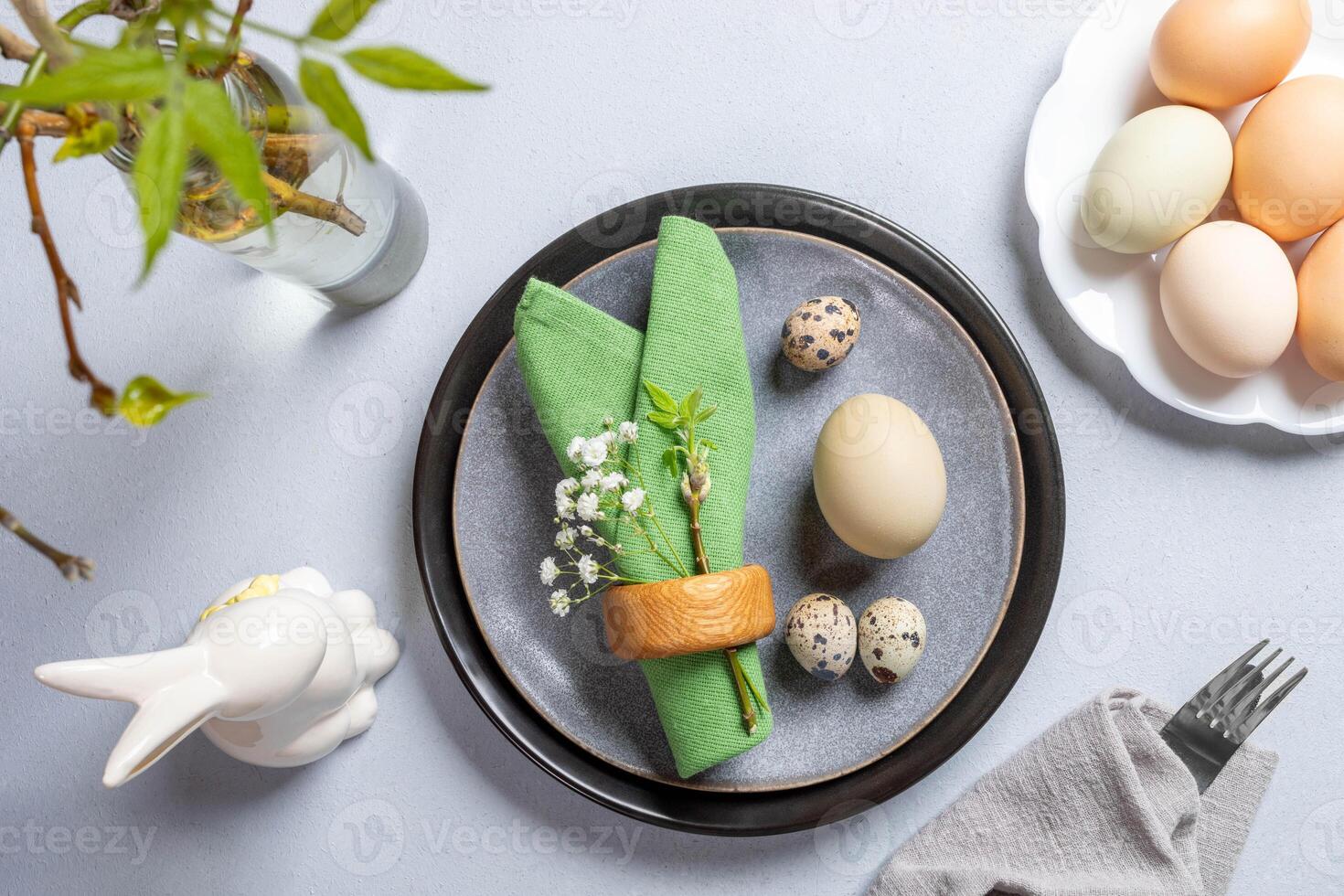 Trendy Easter table Natural colors. Plates, green napkin, organic eggs, cutlery, spring twigs, bunny photo