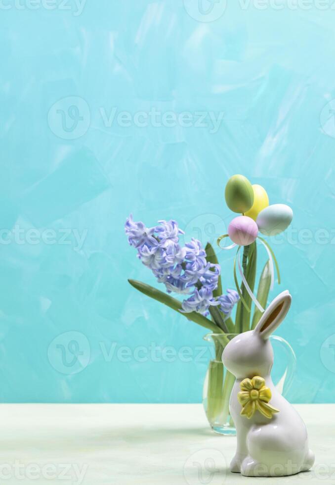 Turquoise Easter card. Color decorative eggs, ceramic bunny, jacinth flower in glass vase Copy space photo