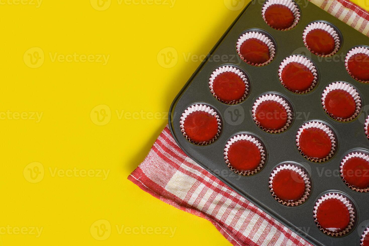 Tray with mix of red velvet cupcake ingredients ready to bake. Yellow background. photo