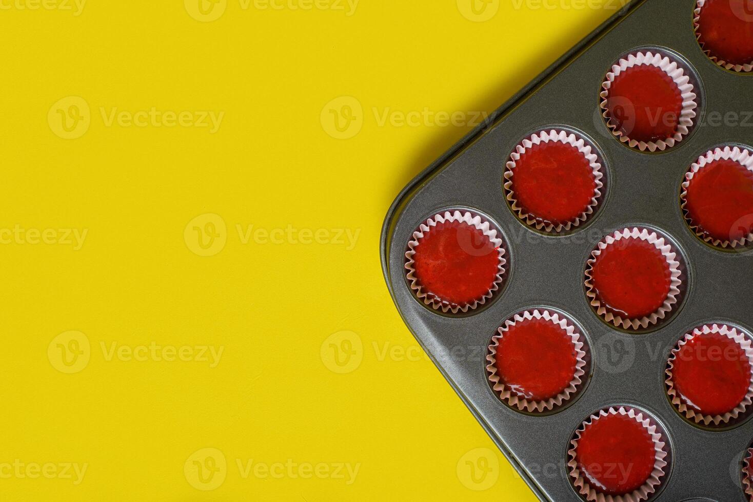 Tray with mix of red velvet cupcake ingredients ready to bake. Yellow background. photo