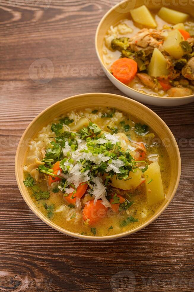 Chicken soup with vegetables in a deep bowl on a wooden table. photo