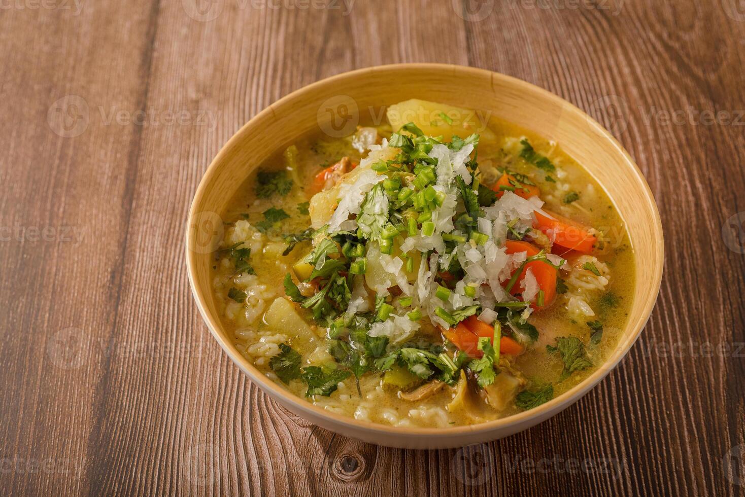 Chicken soup with vegetables in a deep bowl on a wooden table. photo