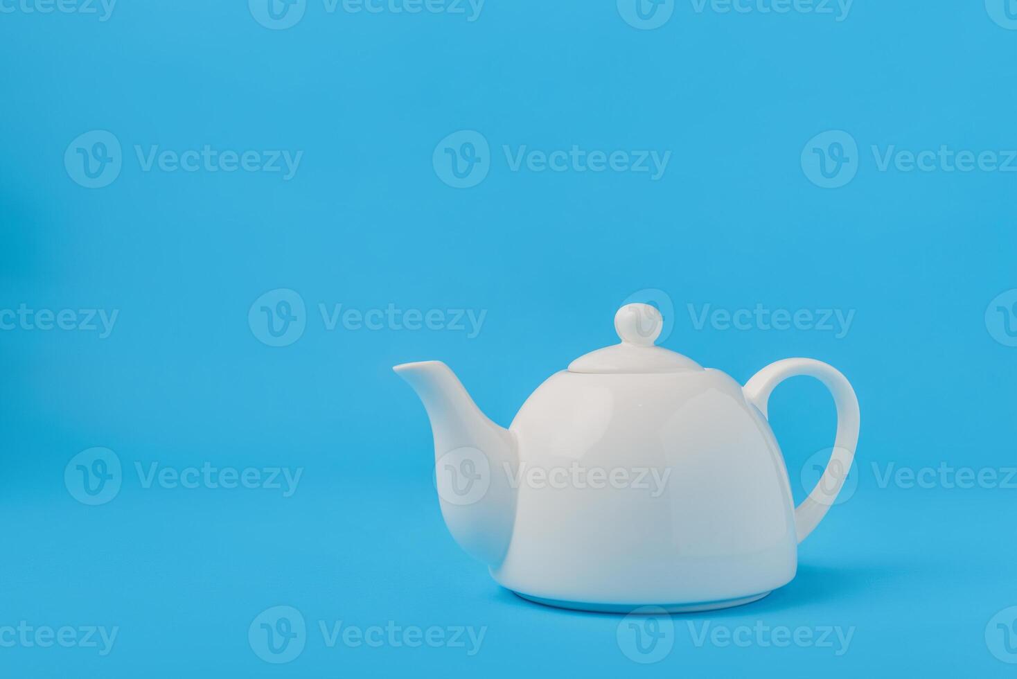 White ceramic teapot isolated on blue background. photo