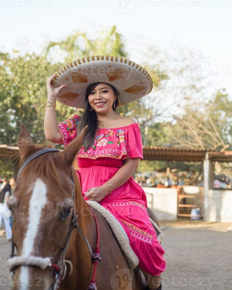 mexicano mujer vistiendo tradicional vestir y charro sombrero en lado de caballo. cinco Delaware mayonesa celebracion. foto