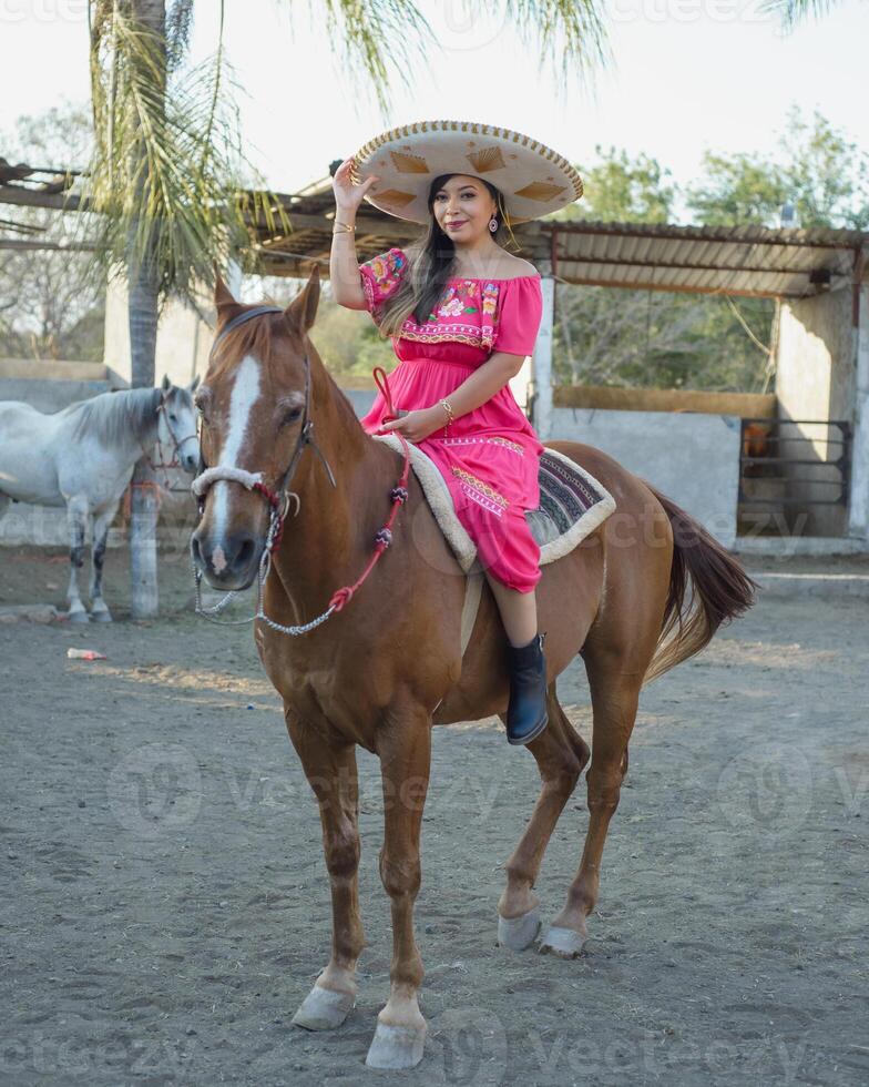 mexicano mujer vistiendo tradicional vestir y charro sombrero en lado de caballo. cinco Delaware mayonesa celebracion. foto