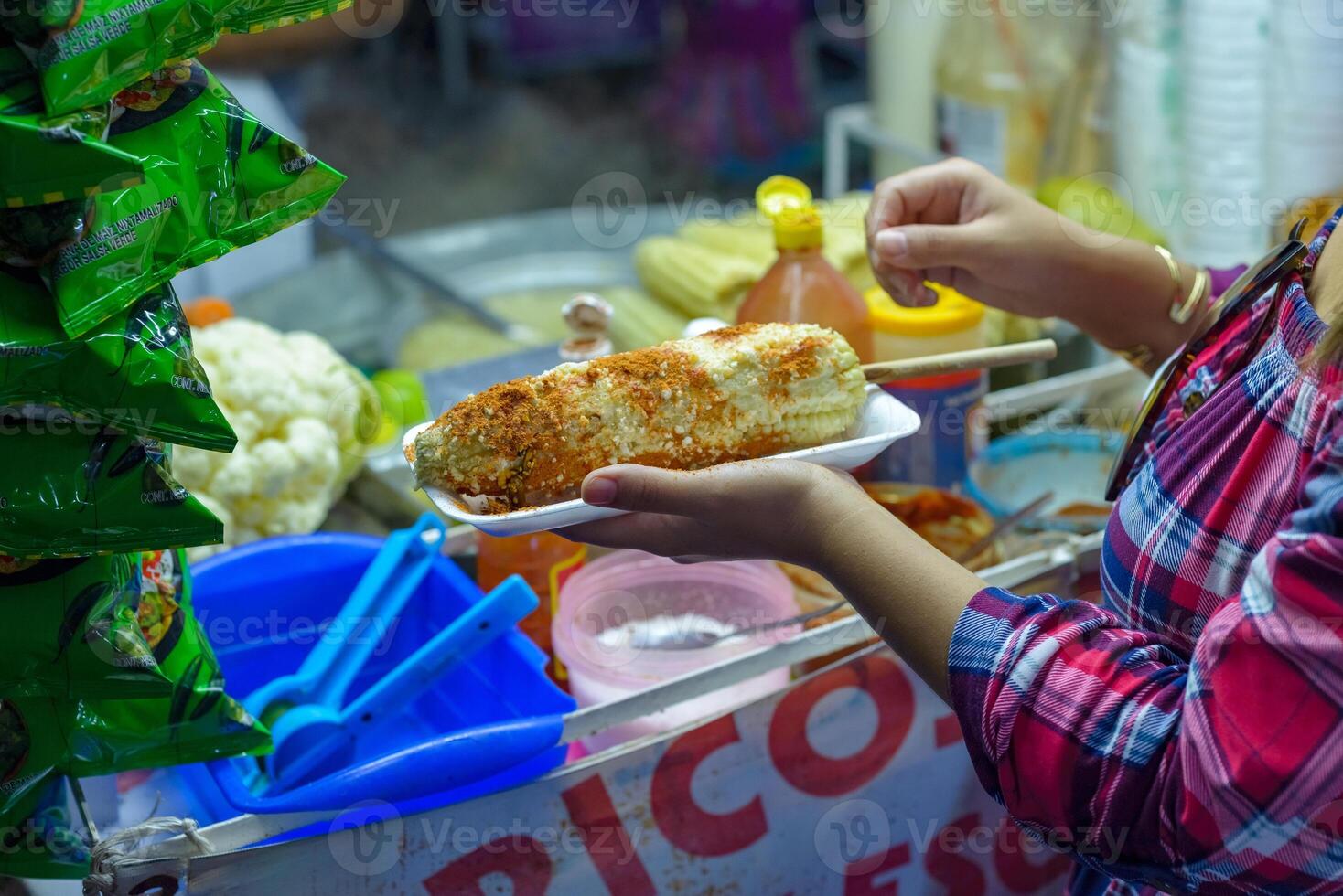 mexicano mujer preparando un hervido maíz, típico mexicano calle alimento. comida parar. elote. foto