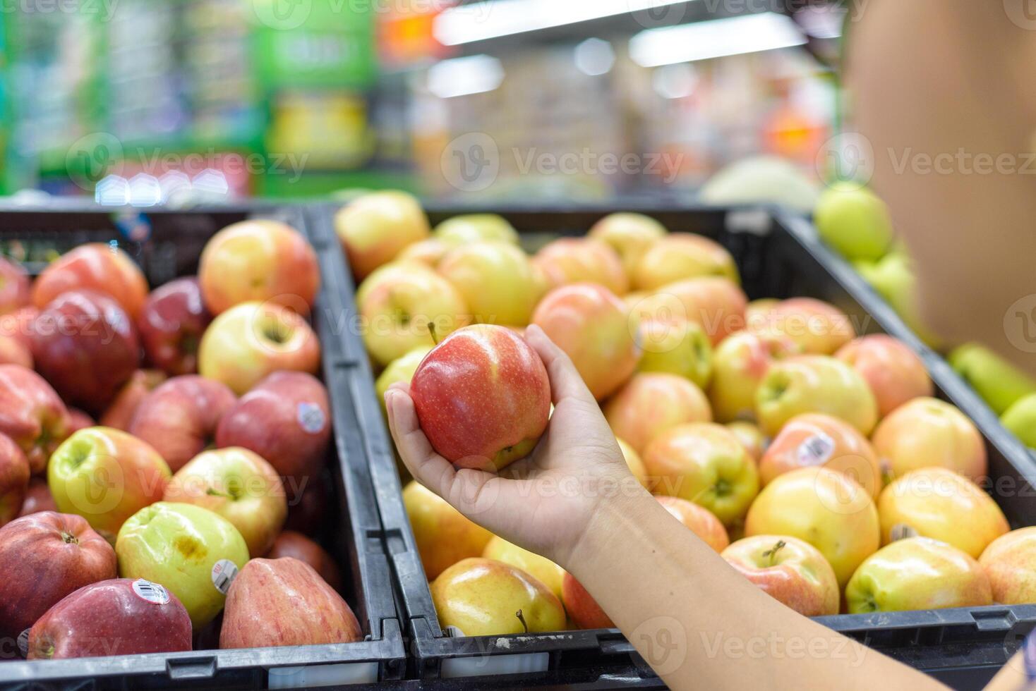 Hand holding an apple at a supermarket. photo