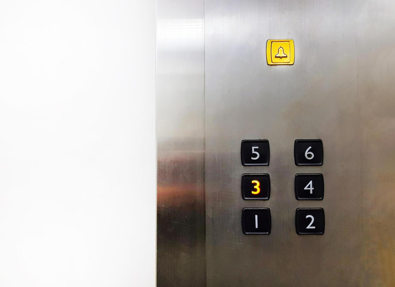 Group of Black Elevator push buttons with yellow bell, warning or alarm buttons on stainless steel background with copy space that shows passenger pressed on third floor for going up or down. photo