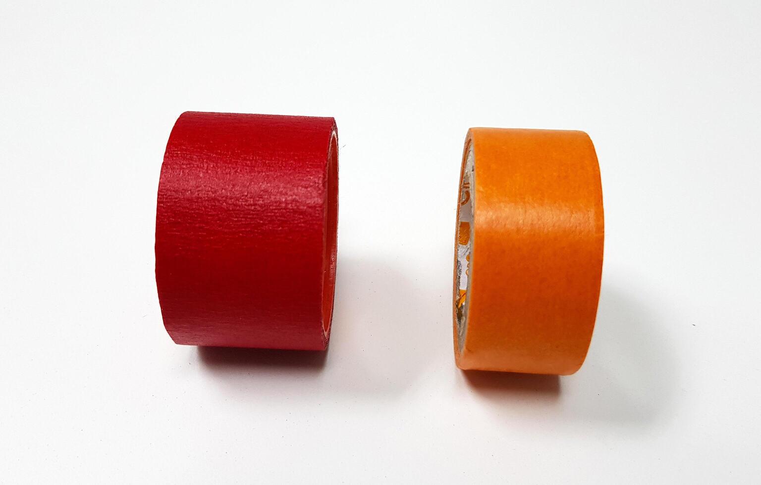 Two masking tapes roll red and orange isolated on white background. Object for stick on paper. photo