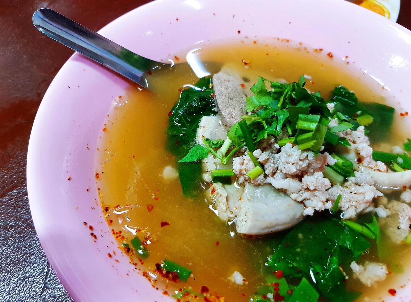 Close up boiled pork blood with minced, entrails and vegetable in pink bowl on table. Asian and hot food. photo