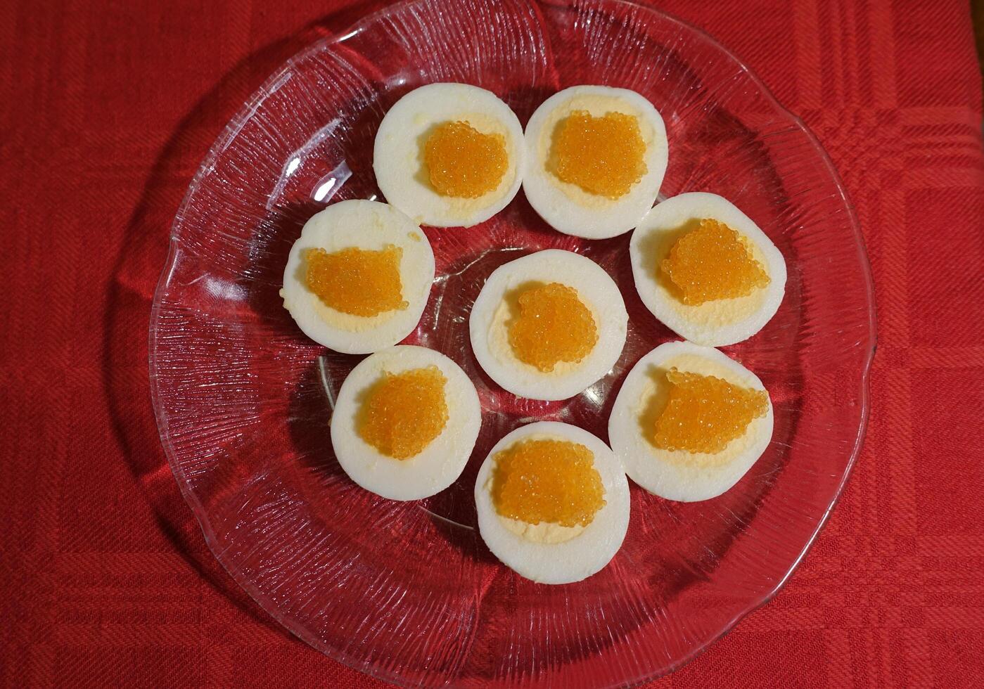 Boiled eggs with fish roe served on a glass plate photo