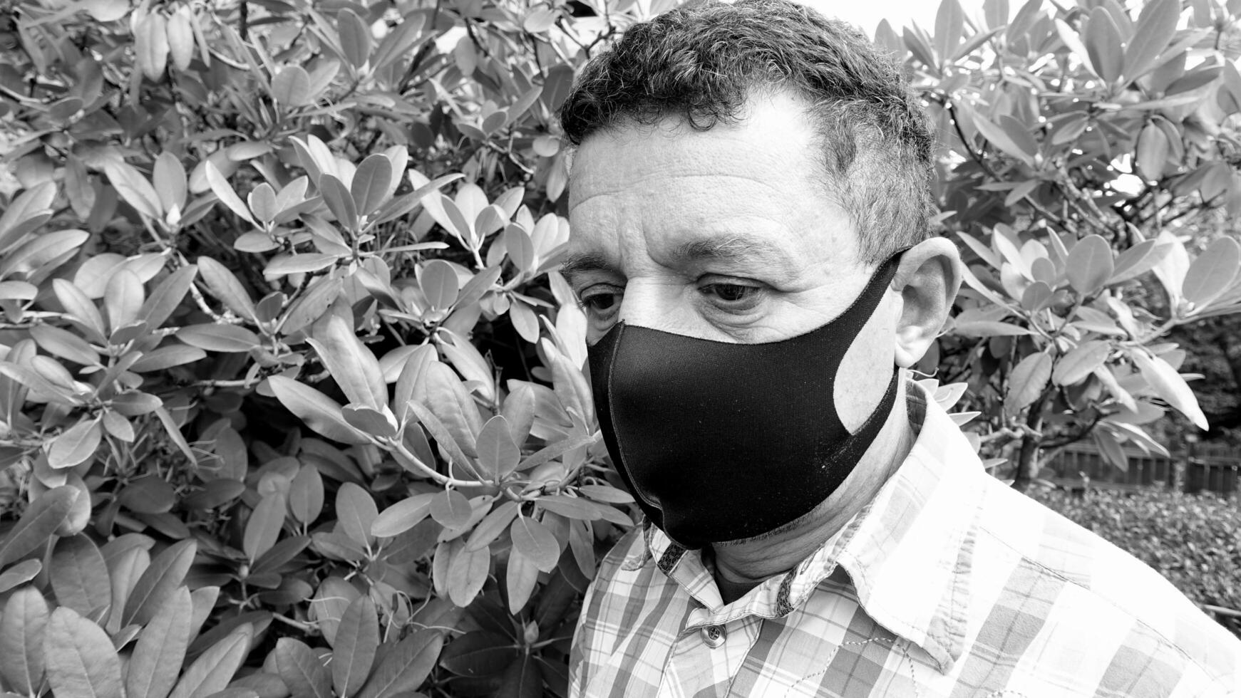 image that portrays the face of a man with a black protective anti-contagion mask photo