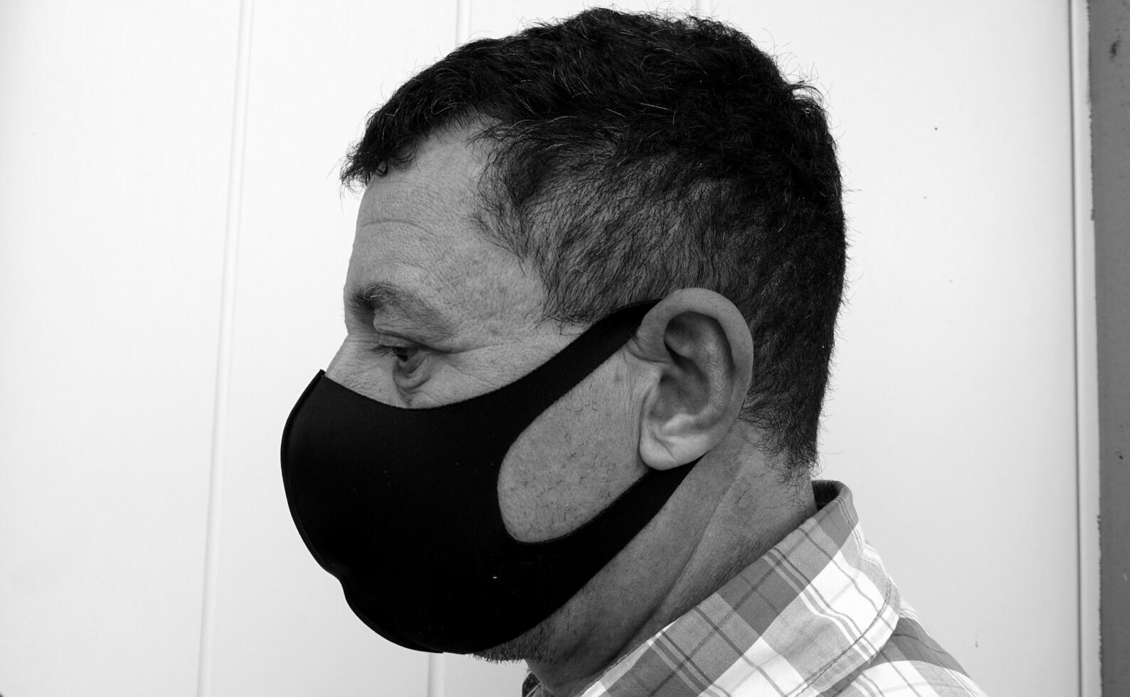 image that portrays the face of a man with a black protective anti-contagion mask photo