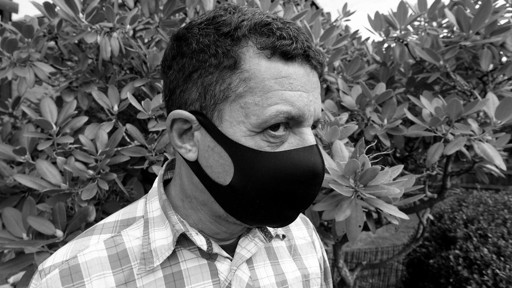 image that portrays the face of a man with a black protective anti-contagion mask photo