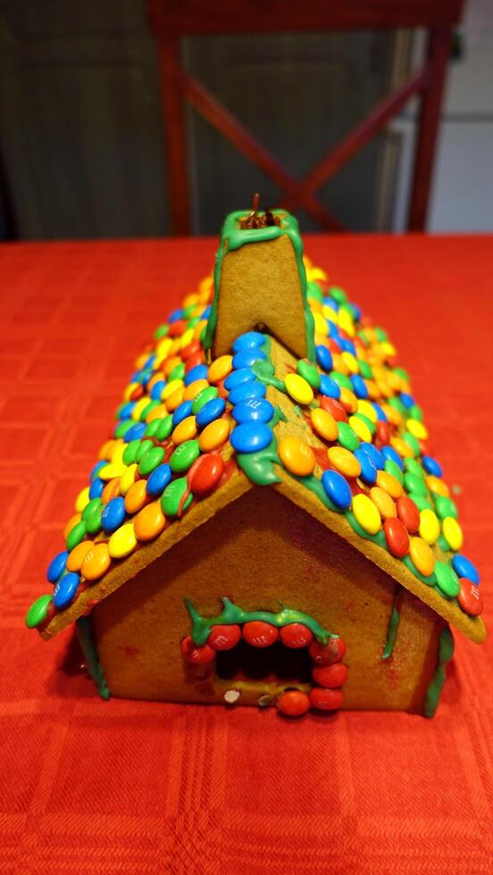 a home-made gingerbread house with the roof covered with chocolates photo