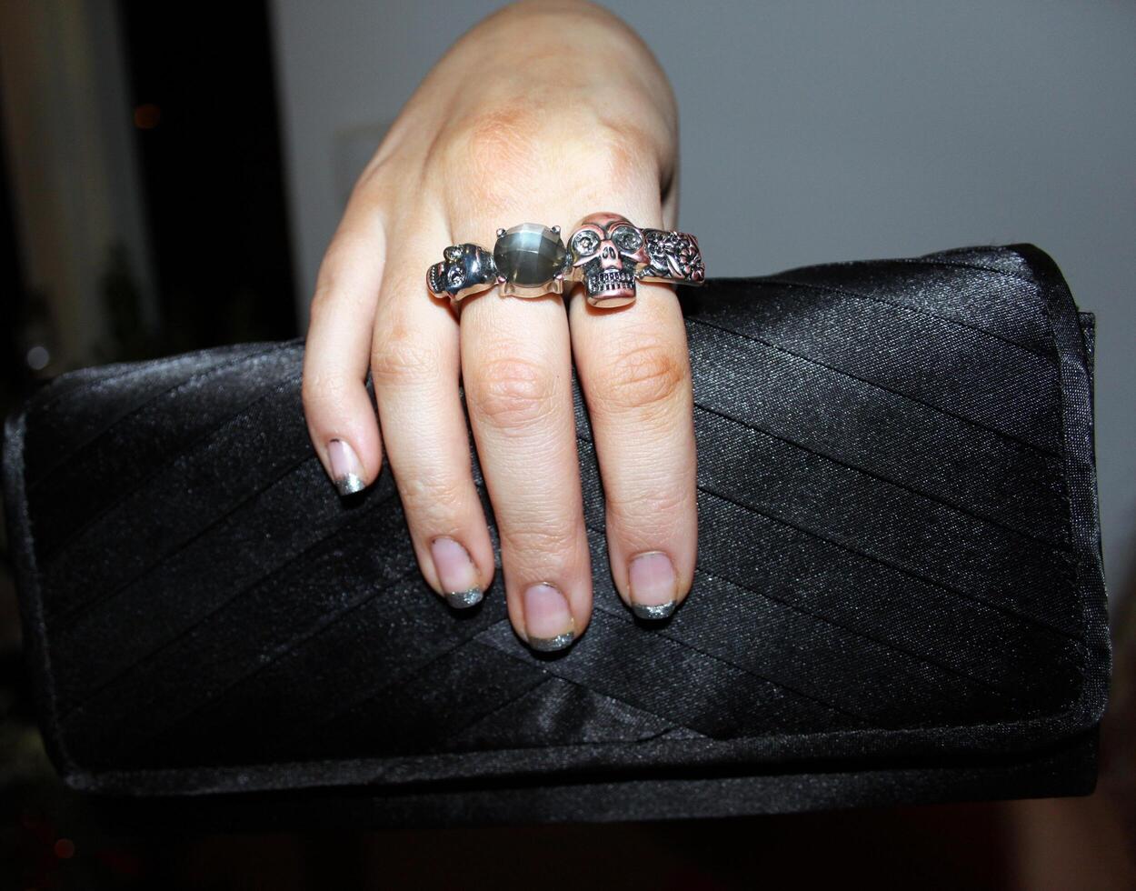 a young hand with many rings on his fingers holds a black photo