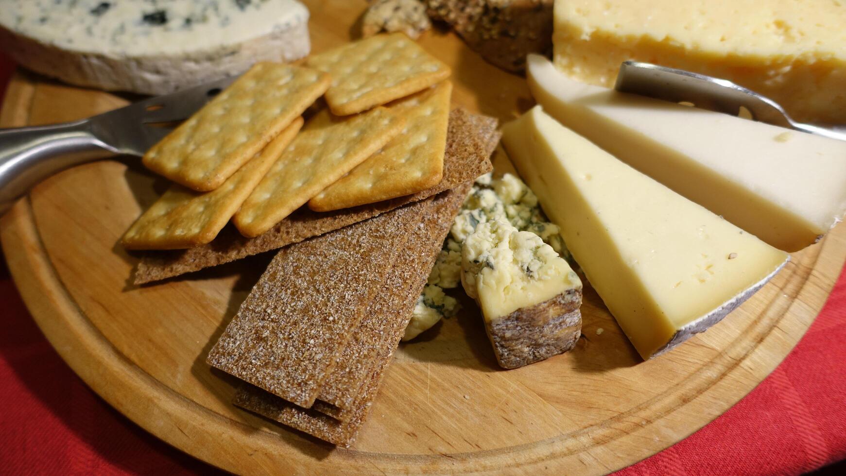 Mixed cow cheeses served on a wooden plate with slices of wholemeal bread photo