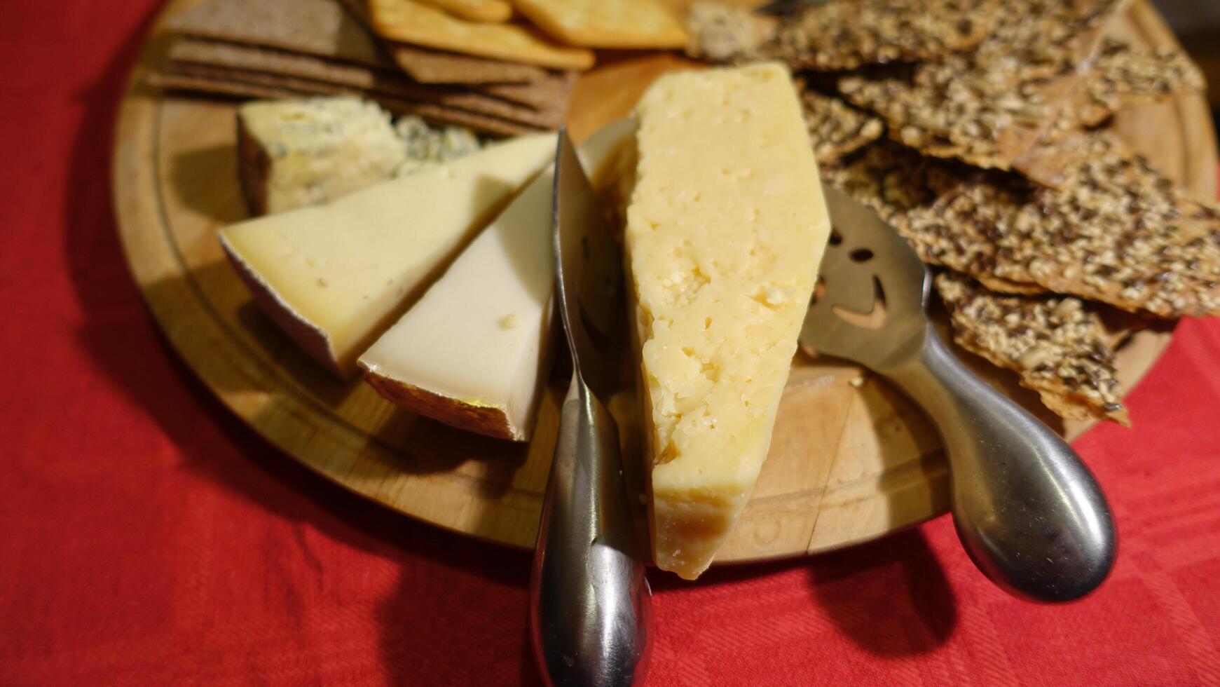 Mixed cow cheeses served on a wooden plate with slices of wholemeal bread photo