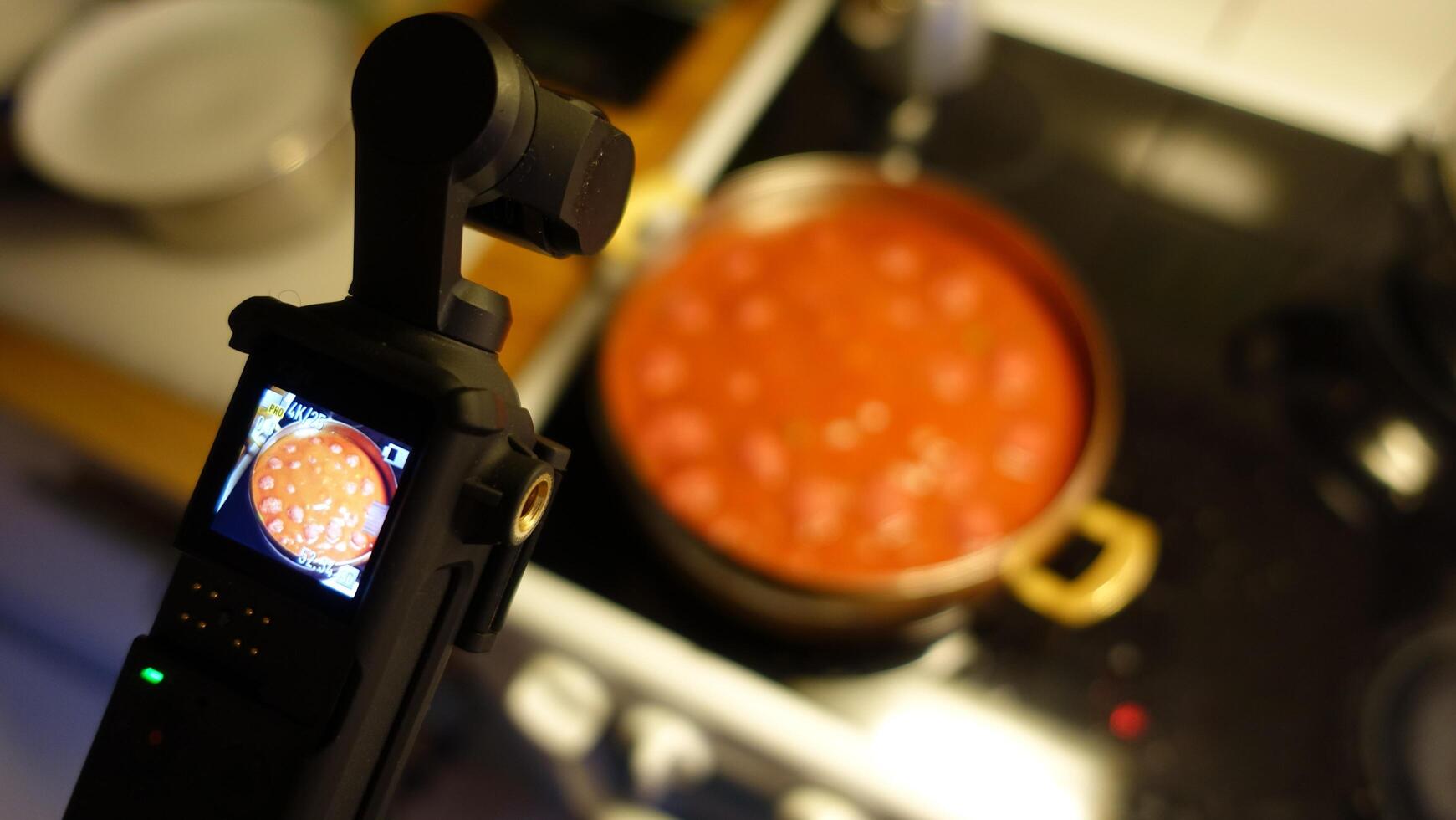 A digital camera is filming homemade meatballs simmering in tomato sauce photo