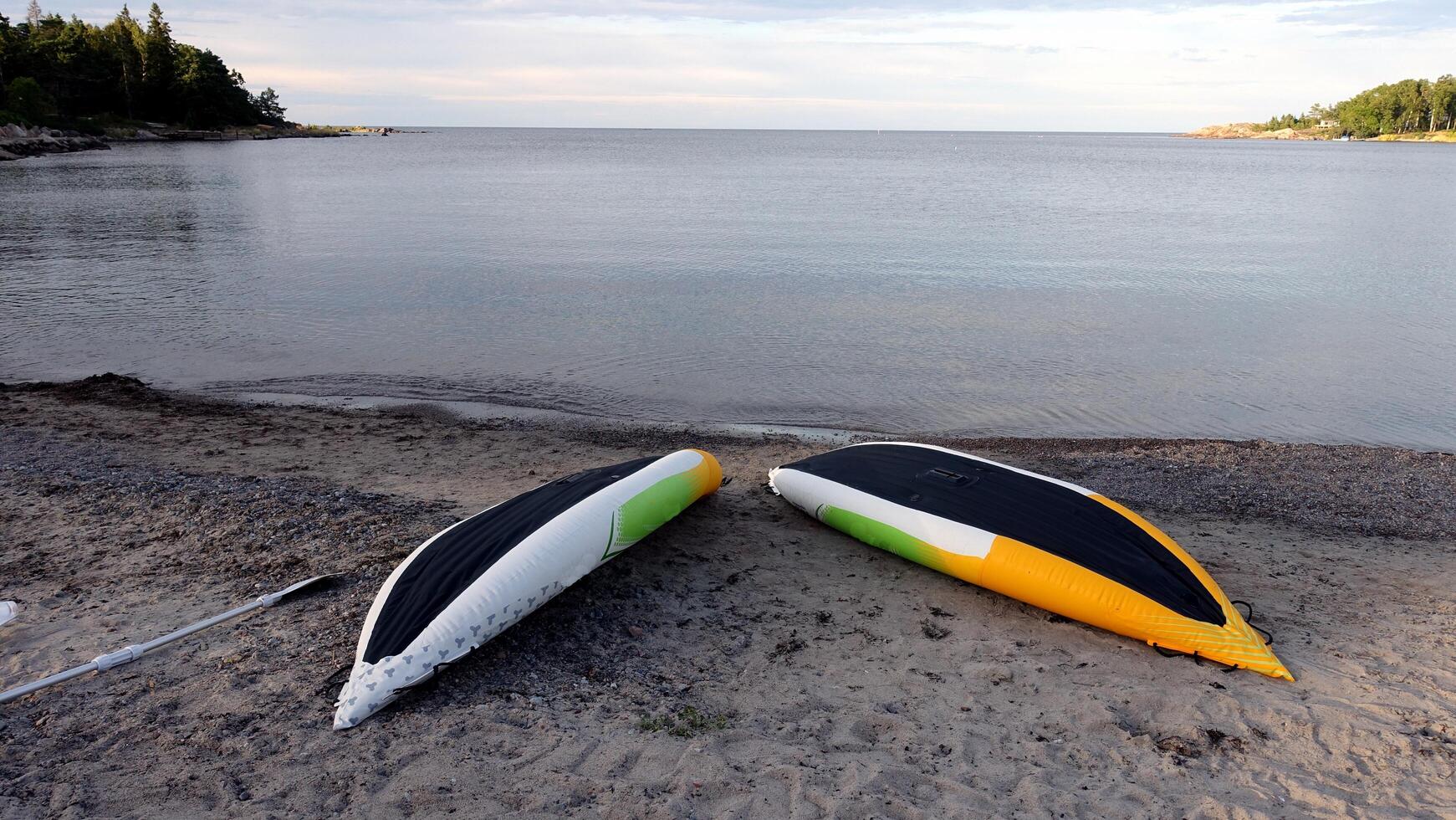 two yellow, white and green canoes placed upside down on the beach to dry after a row photo