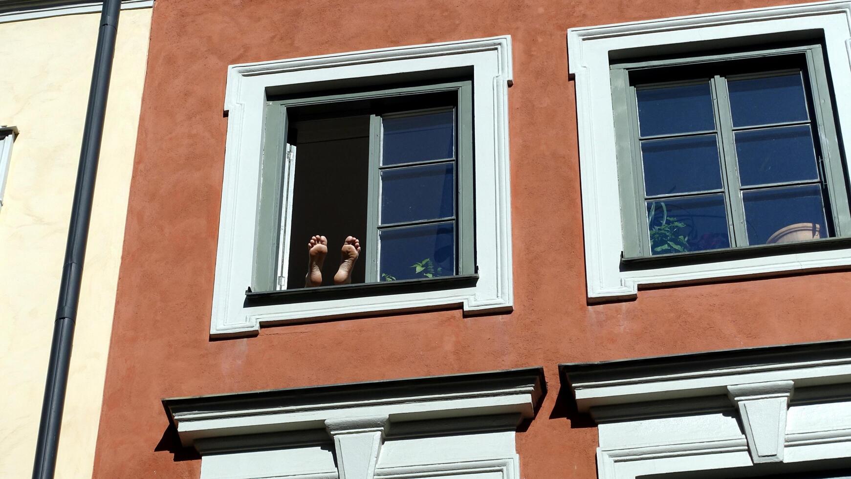 dos pies arriba surgir desde un ventana en el histórico centro. foto