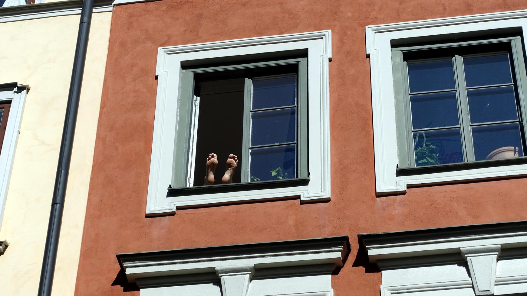 Two feet up emerge from a window in the historic center. photo