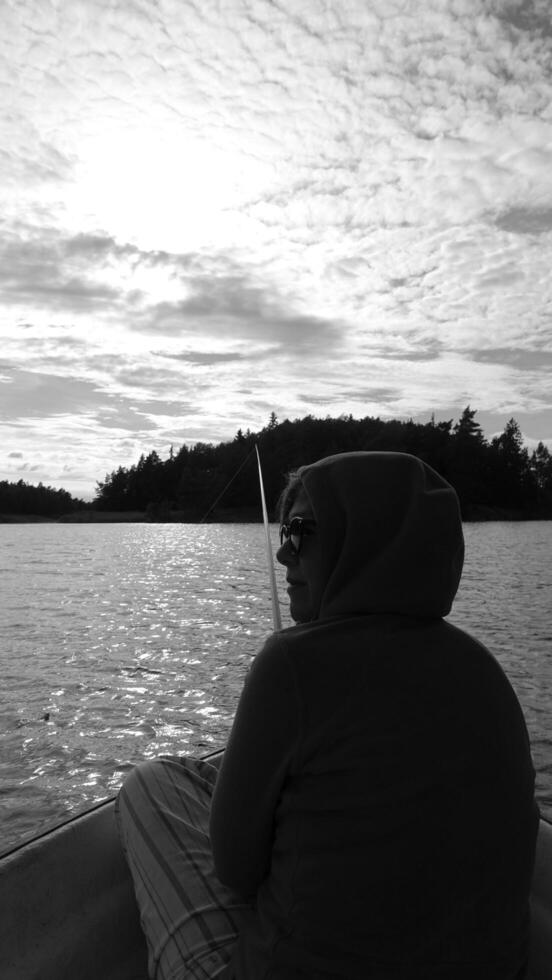 Black and white photo of a woman from behind, resting while fishing