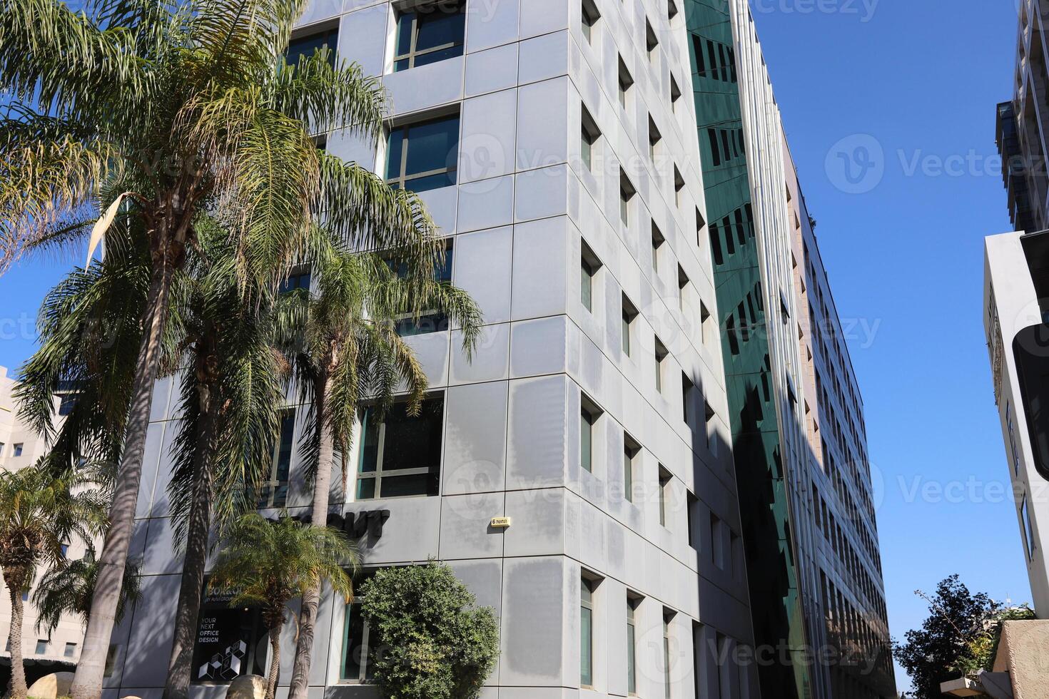 Tel Aviv Israel 03 28 2024. Buildings and structures in Tel Aviv through the foliage of tall trees. photo