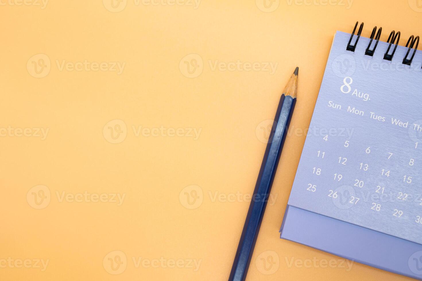 August Calendar and pencil isolated on orange background, planning for business or travel planning concept. Copy space for text. photo