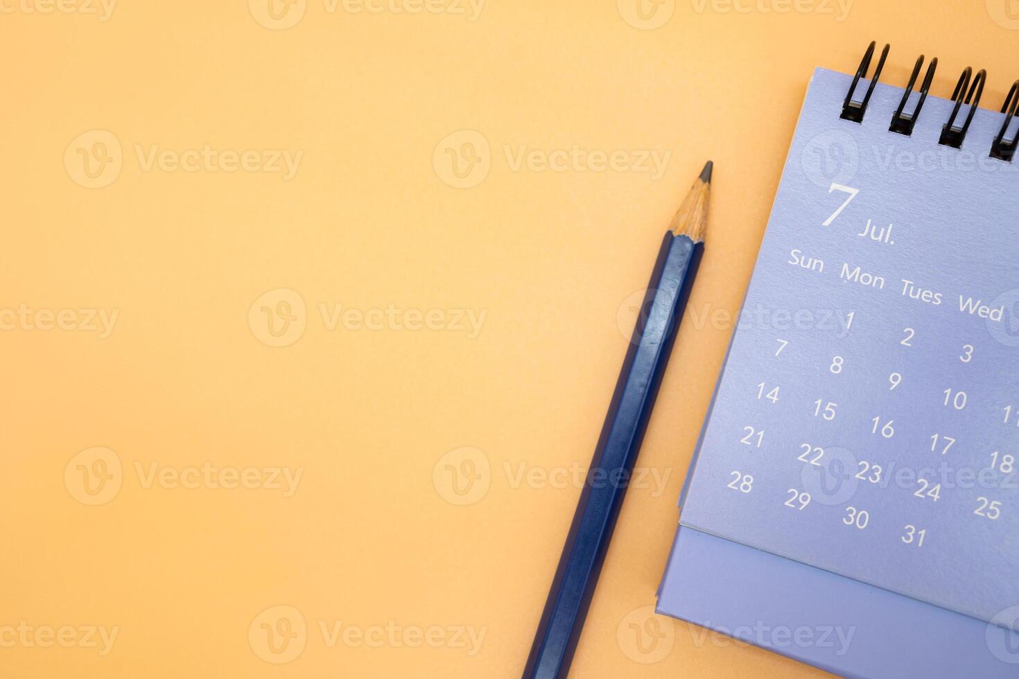 July Calendar and pencil isolated on orange background, planning for business or travel planning concept. Copy space for text. photo