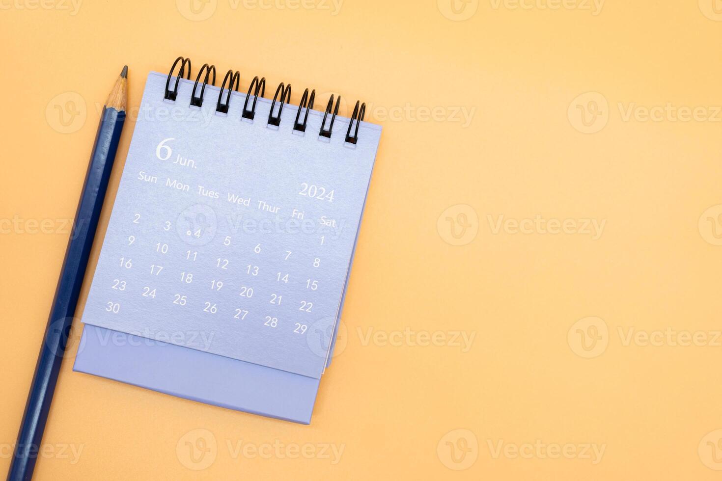 2024 June Calendar and pencil isolated on orange background. planning for business or travel concept. Copy space for text. photo