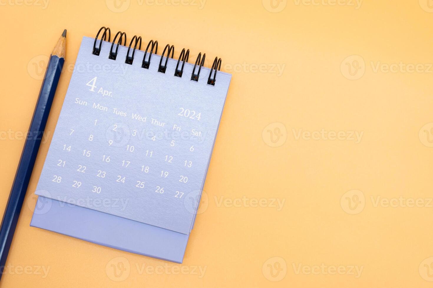2024 April Calendar and pencil isolated on orange background. planning for business or travel concept. Copy space for text. photo