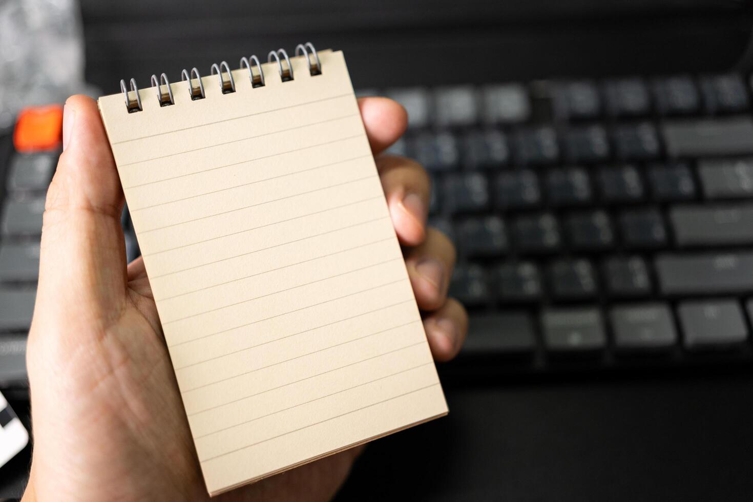 Hand holding Spiral notepad. Blank one face brown paper note. empty sheet of brown lined photo