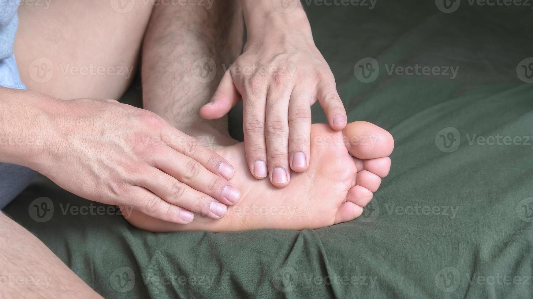 Man massaging the arch of the soles of his feet with his hands photo