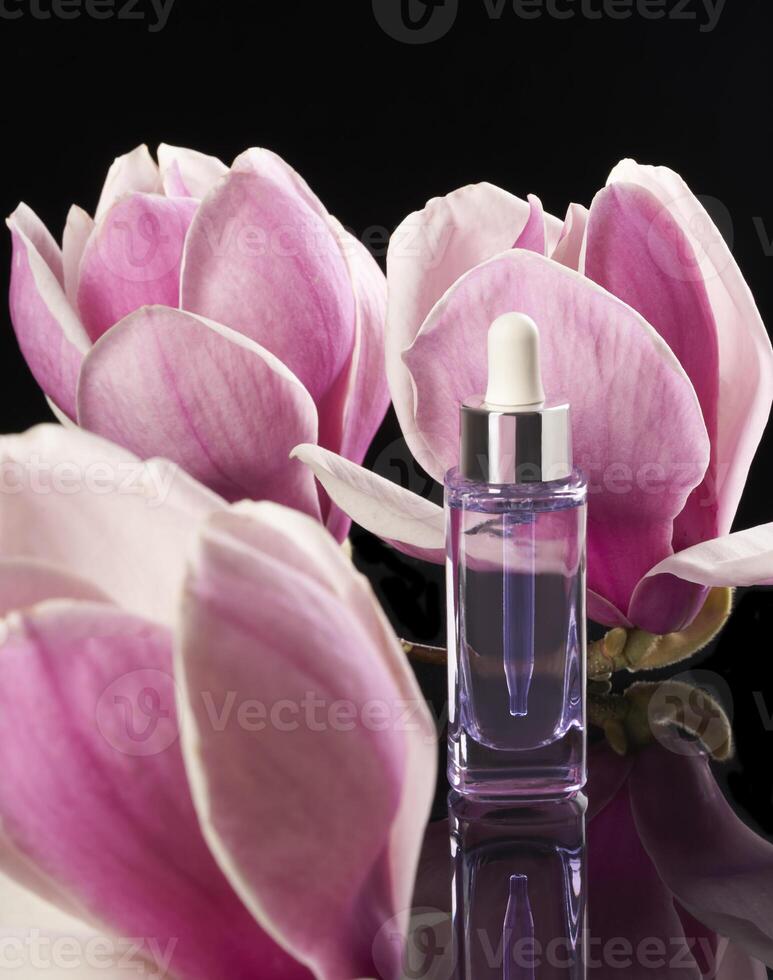 a bottle of perfume with a pink flower in the black background photo