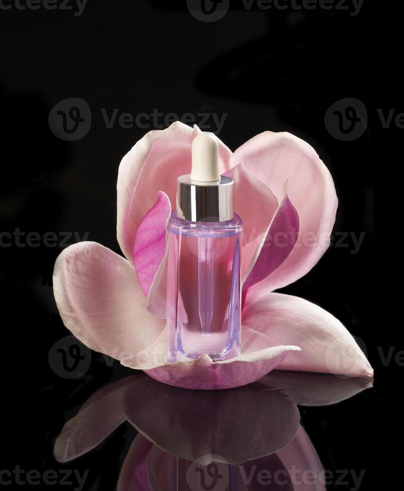 a bottle of perfume with a pink flower in the black background photo