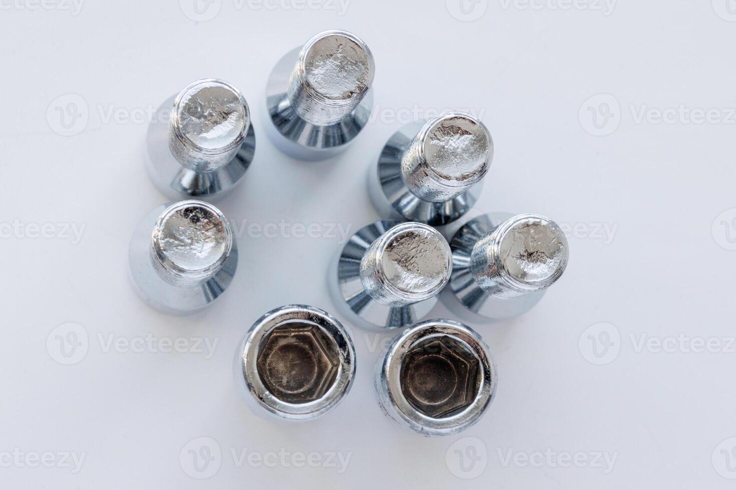 shiny steel chrome coated wheel bolts on white background, full-frame closeup high angle view photo