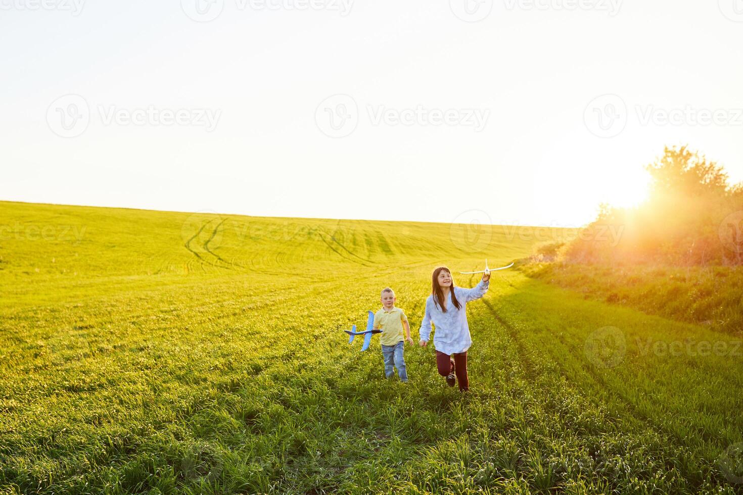 Cheerful and happy children play in the field and imagine themselves to be pilots on a sunny summer day. Kids dreams of flying and aviation. photo