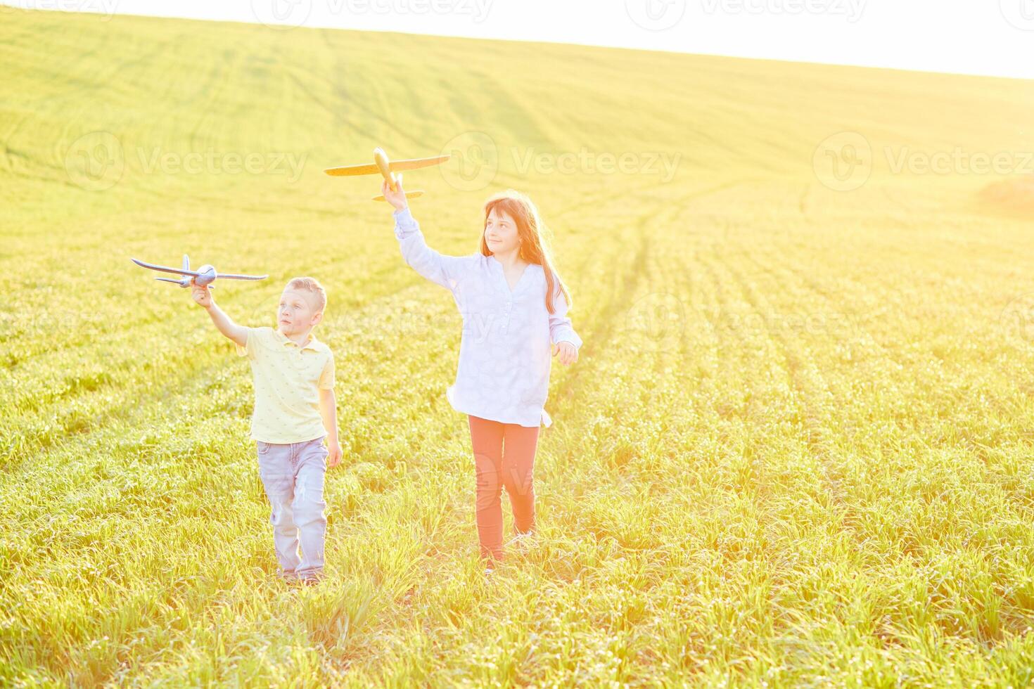 Cheerful and happy children play in the field and imagine themselves to be pilots on a sunny summer day. Kids dreams of flying and aviation. photo