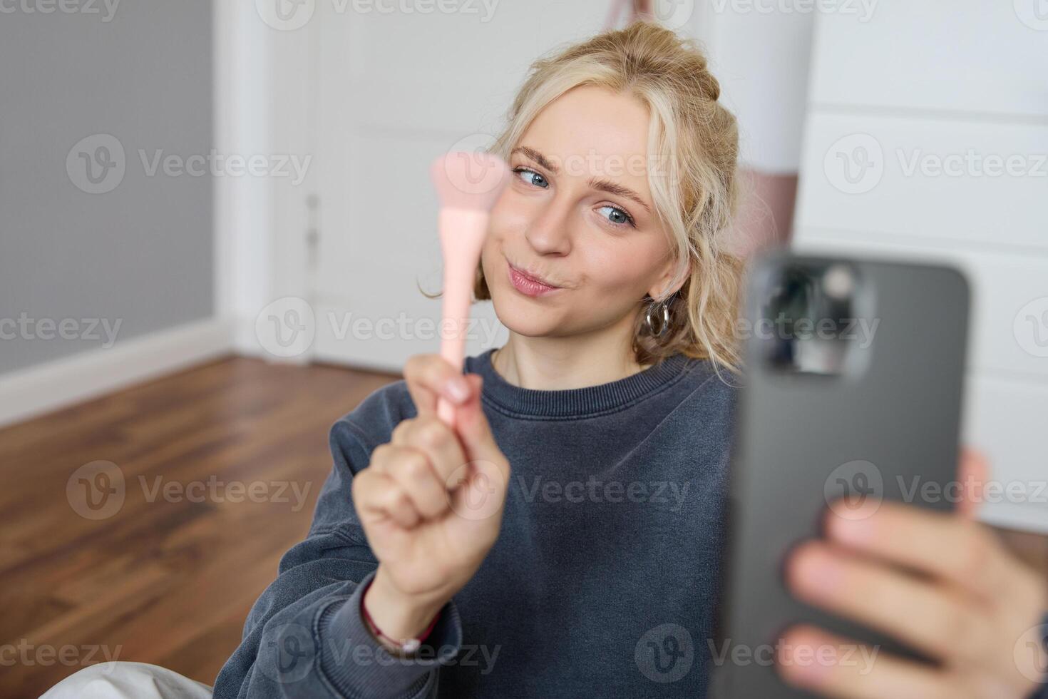 Portrait of young woman, girl beauty blogger, recording vlog in her bedroom, doing makeup tutorial for social media followers, taking selfies, live streaming on mobile phone app photo