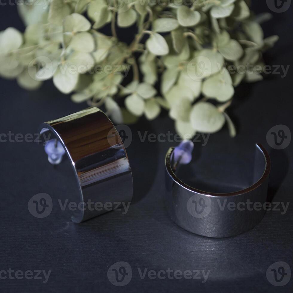 Silver earrings on a black background with decor photo