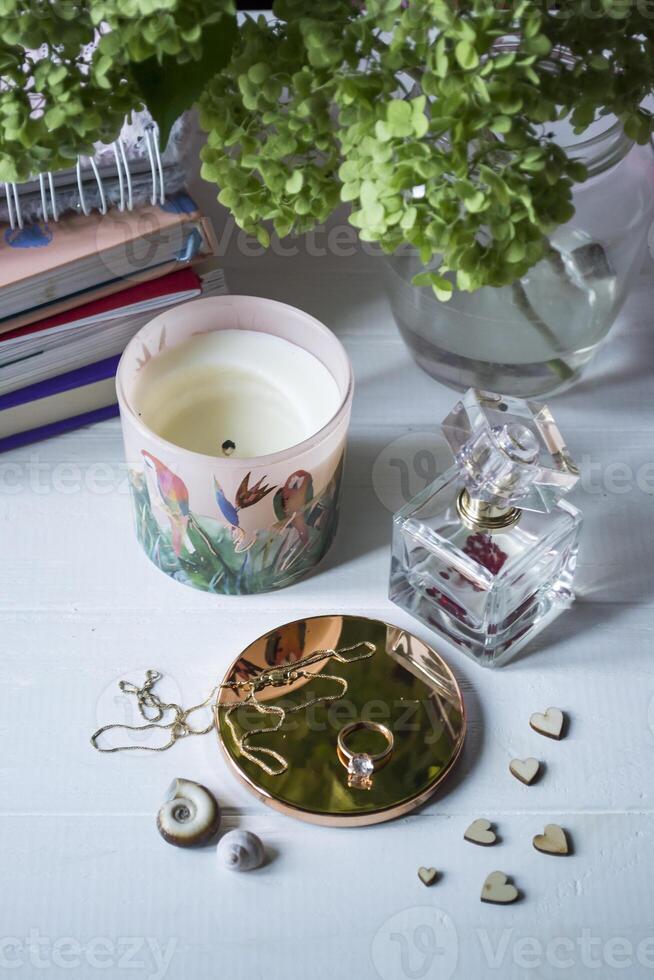Candle, perfume bottle and jewels on a white table. photo